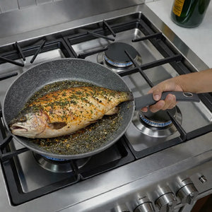 Sartén Bergner Orion Ø32 cm gris tipo piedra con antiadherente Marble+ cocinando pescado en estufa de gas, mango soft-touch.