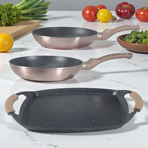 Set Berlinger Haus Metallic Line Rose Gold BH-1669: sartén 22 cm, sartén 26 cm y plancha 36×23 cm, vista lateral sobre encimera blanca.