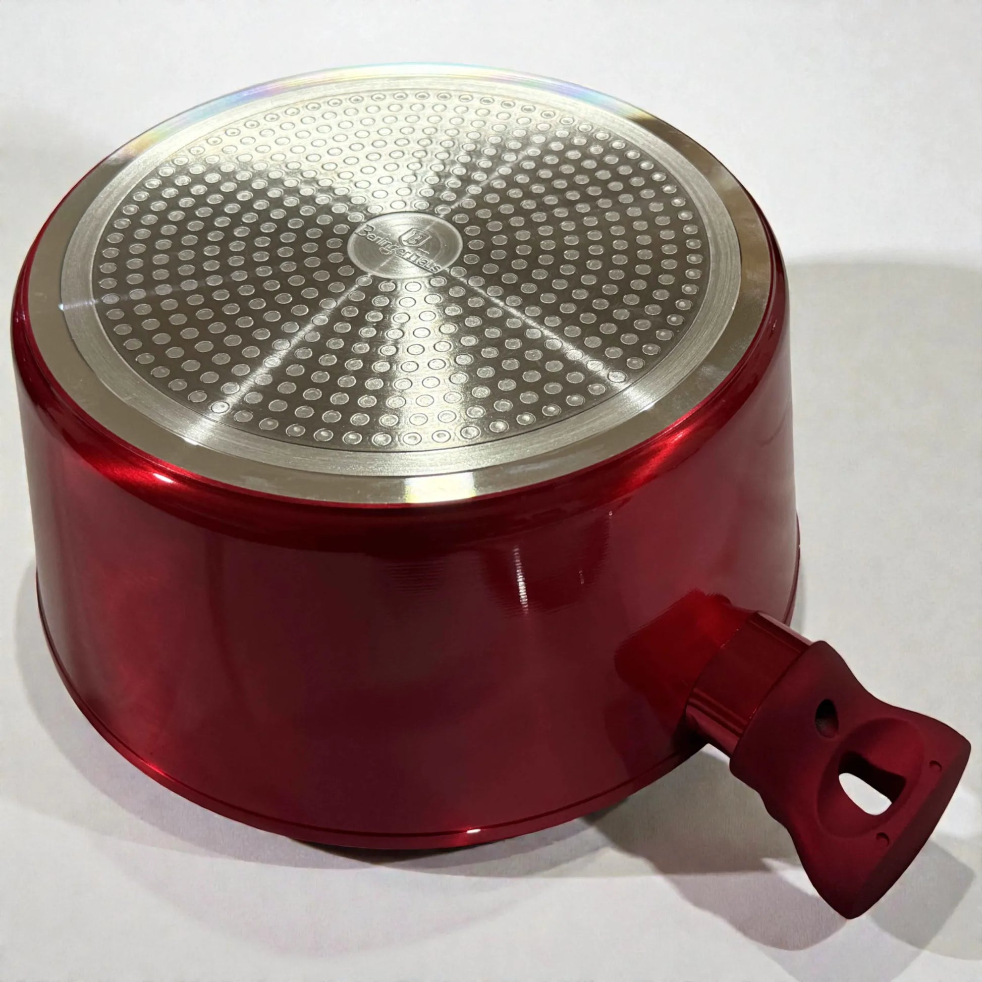 Vista inferior de una olla Berlinger Haus Metallic Line Burgundy mostrando la base compatible con induccion y el acabado exterior borgona metalizado, cuerpo de aluminio forjado.