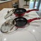 Sarten 20 cm y sarten honda 24 cm Berlinger Haus Metallic Line Burgundy con tapas de vidrio al lado, vista lateral sobre encimera, interior negro con recubrimiento antiadherente tipo marmol.