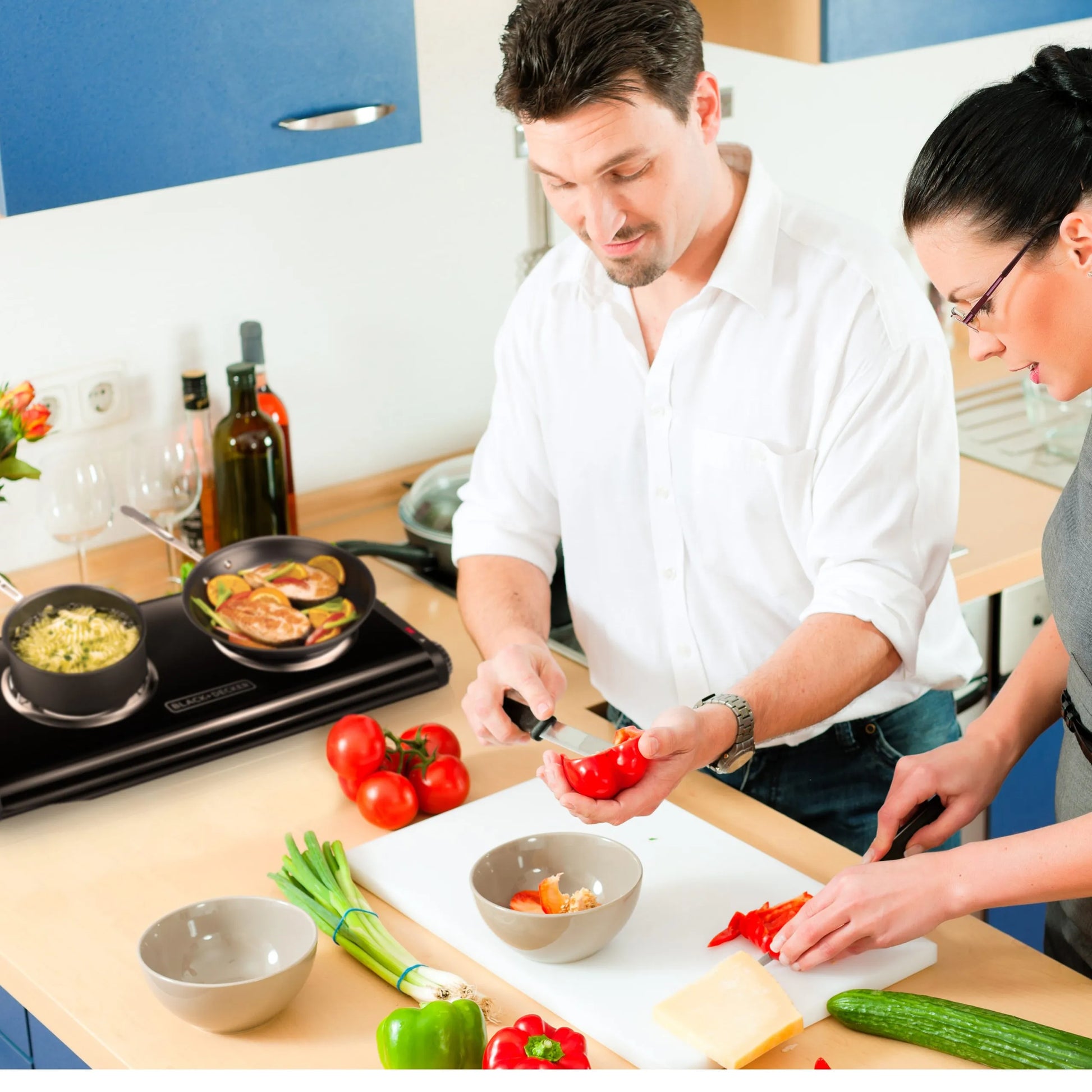 Hornilla eléctrica doble Black+Decker DB1002B negra en uso sobre encimera, cocinando con sartén y olla al mismo tiempo en cocina doméstica.