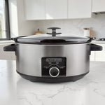 Olla de cocción lenta BLACK+DECKER SC2007S de 7 litros en acero inoxidable con tapa de vidrio y perilla de control, vista frontal en cocina.