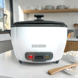 Arrocera Black+Decker RC5200 blanca con tapa negra, vista frontal en cocina, luces Cook y Warm y tazón de arroz al lado.