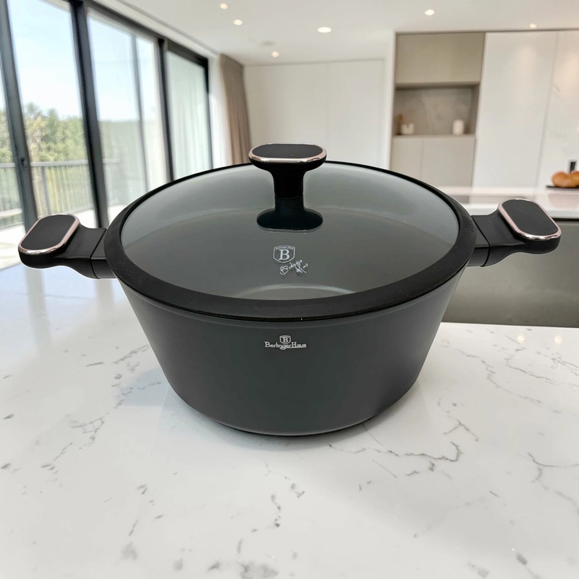 Cacerola mediana Berlinger Haus BH-8362 Black Rose Collection en color negro con tapa de vidrio, pomo central y asas laterales sobre encimera blanca.