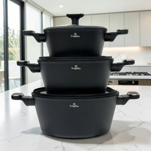 Tres cacerolas Berlinger Haus BH-8362 Black Rose Collection apiladas en color negro con tapas de vidrio y asas laterales sobre encimera blanca.