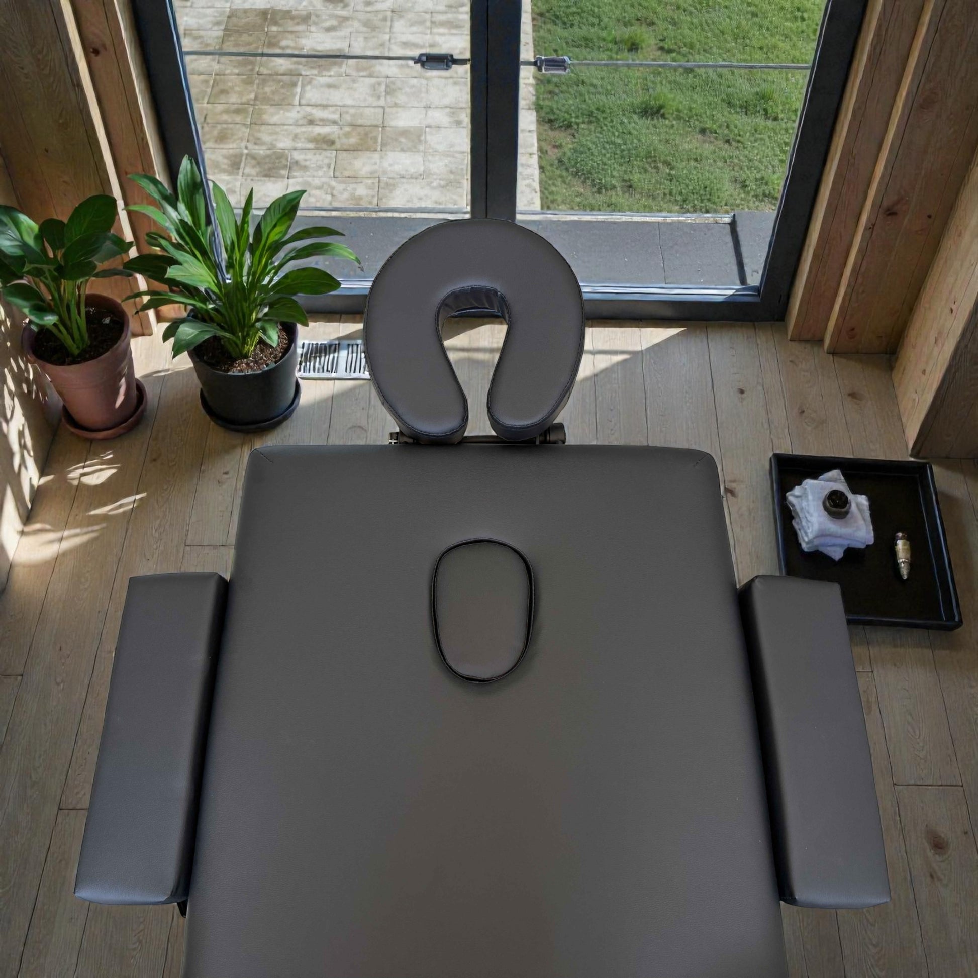 Detalle de la zona de cabeza de la cama de masaje Lotus plegable, con reposacabezas acolchado en U y tapón cubriendo el orificio facial sobre superficie negra ergonómica.