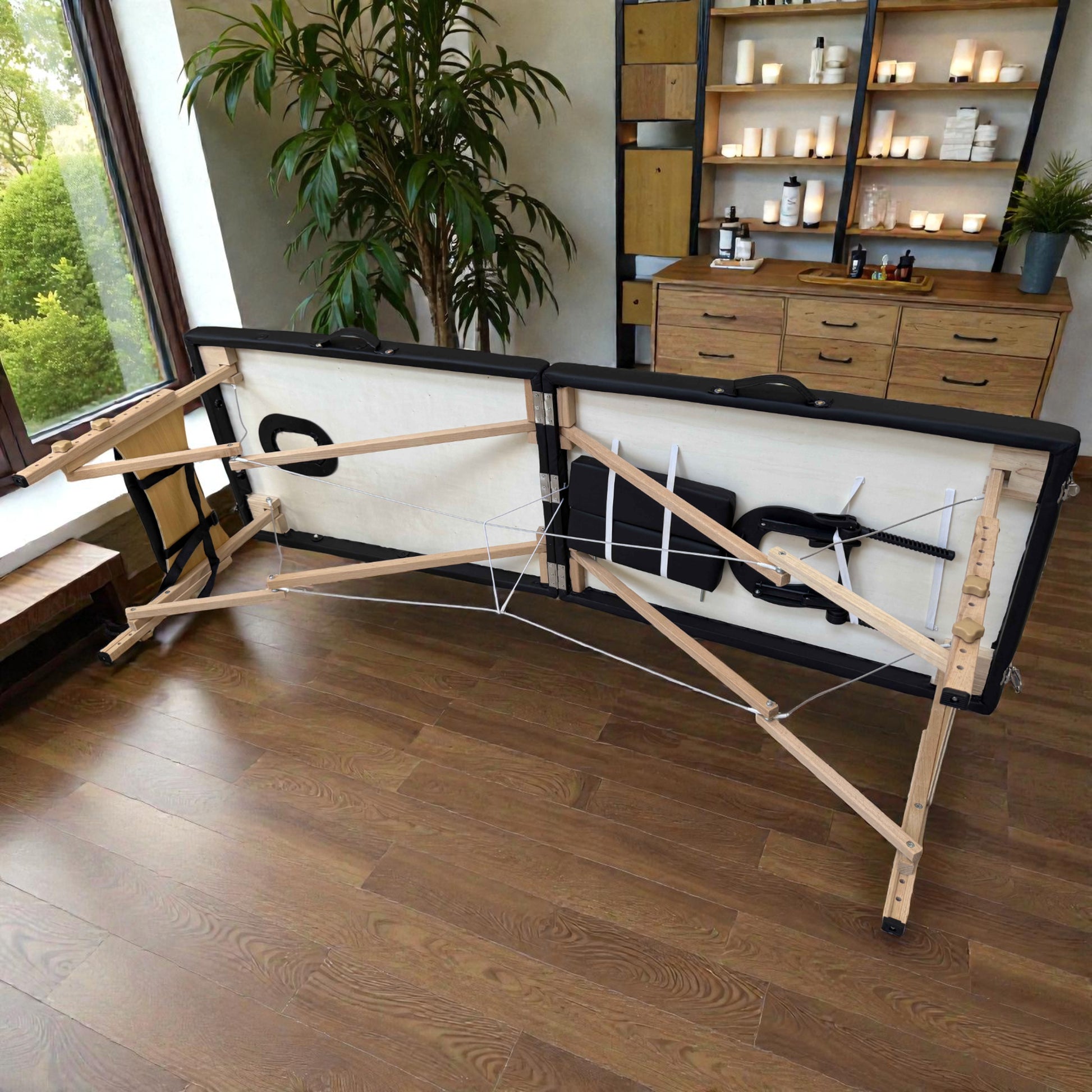 Vista interior de la cama de masaje plegable Lotus negra en proceso de armado, mostrando patas de madera con sistema de tijera, cables tensores y compartimento para cabezal y apoyabrazos.