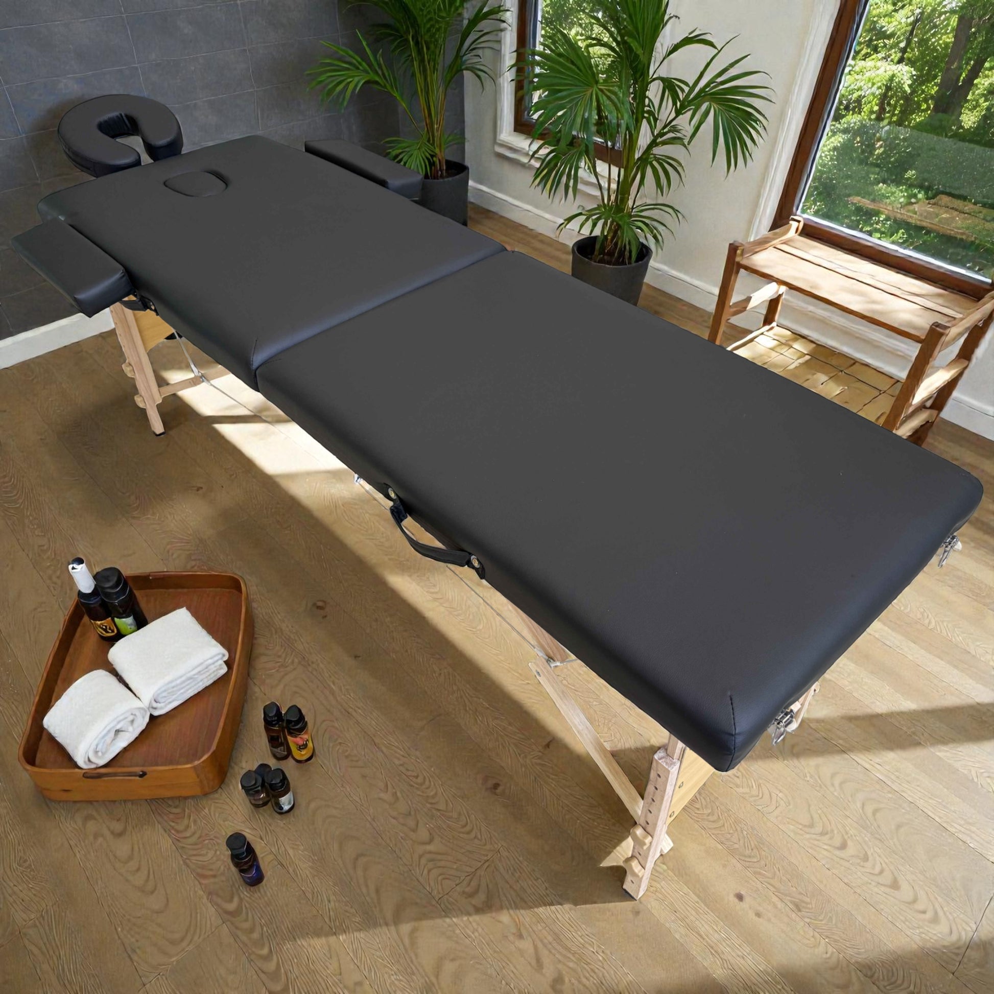 Cama de masaje portátil Lotus Home Collection negra, vista lateral en diagonal, con estructura de madera, altura ajustable y accesorios de aromaterapia alrededor.