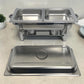 Chafing dish doble de acero inoxidable con tapa retirada al frente y dos bandejas listas para buffet.
