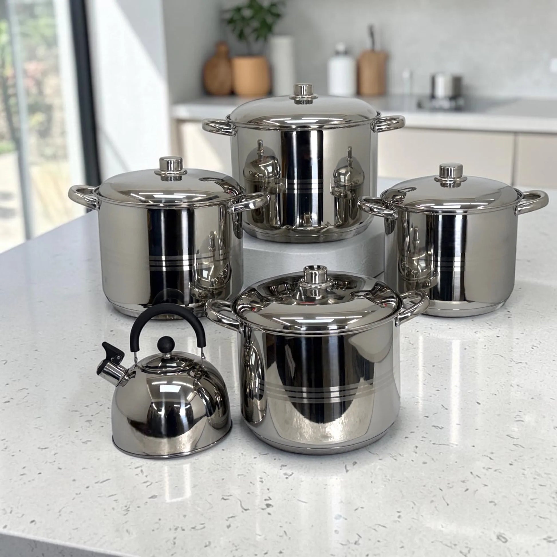 Juego de ollas Crystal Cuisine CC-138 de acero inoxidable de 10 piezas con tetera, vista frontal completa con cuatro ollas de distintos tamanos y tapas metalicas sobre mesa de cocina.