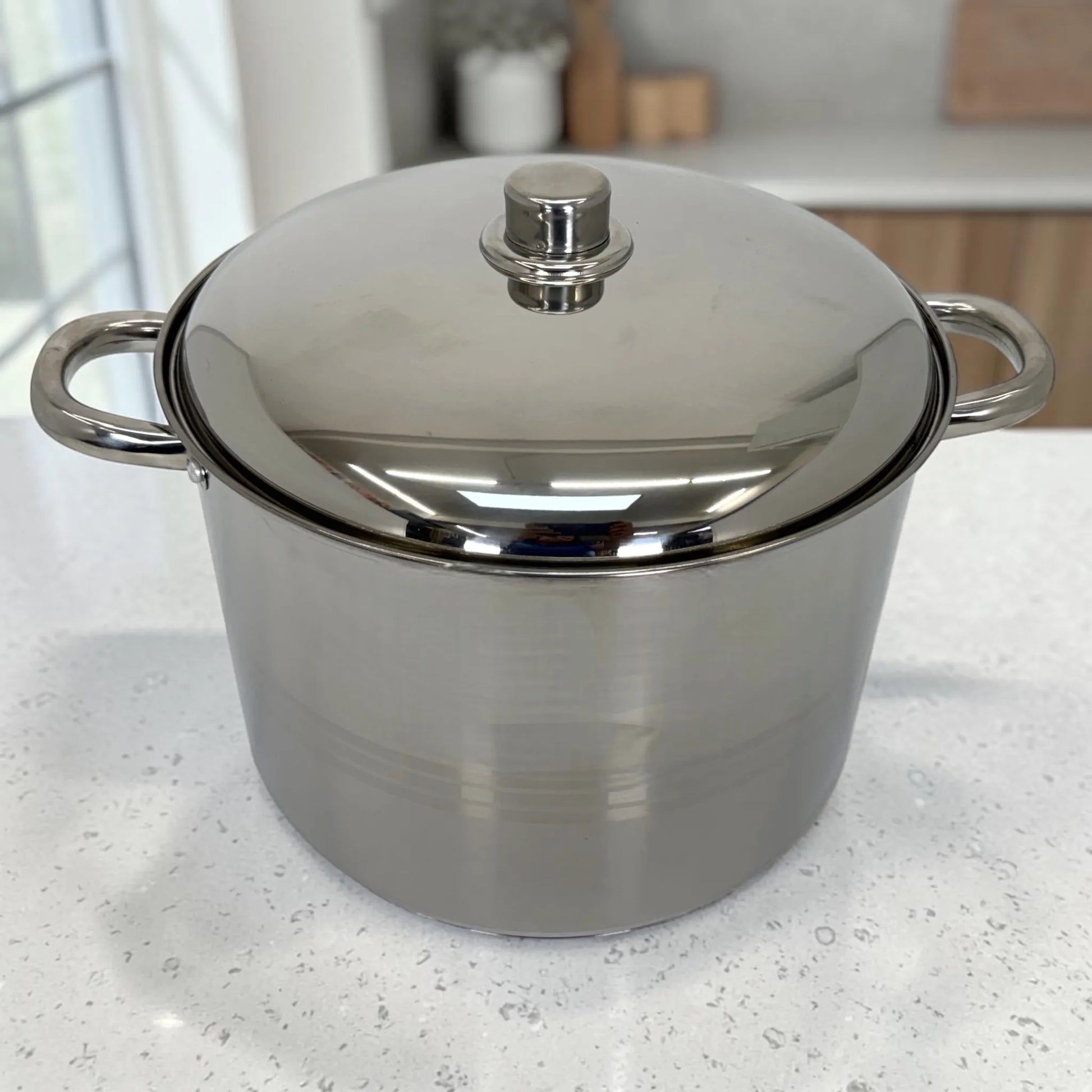 Olla grande Crystal Cuisine CC-138 de acero inoxidable con tapa metalica, vista frontal sobre encimera blanca de cocina moderna.