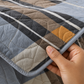 Detalle del tejido acolchado de microfibra con cuadros azul, gris, café, marfil y mostaza.