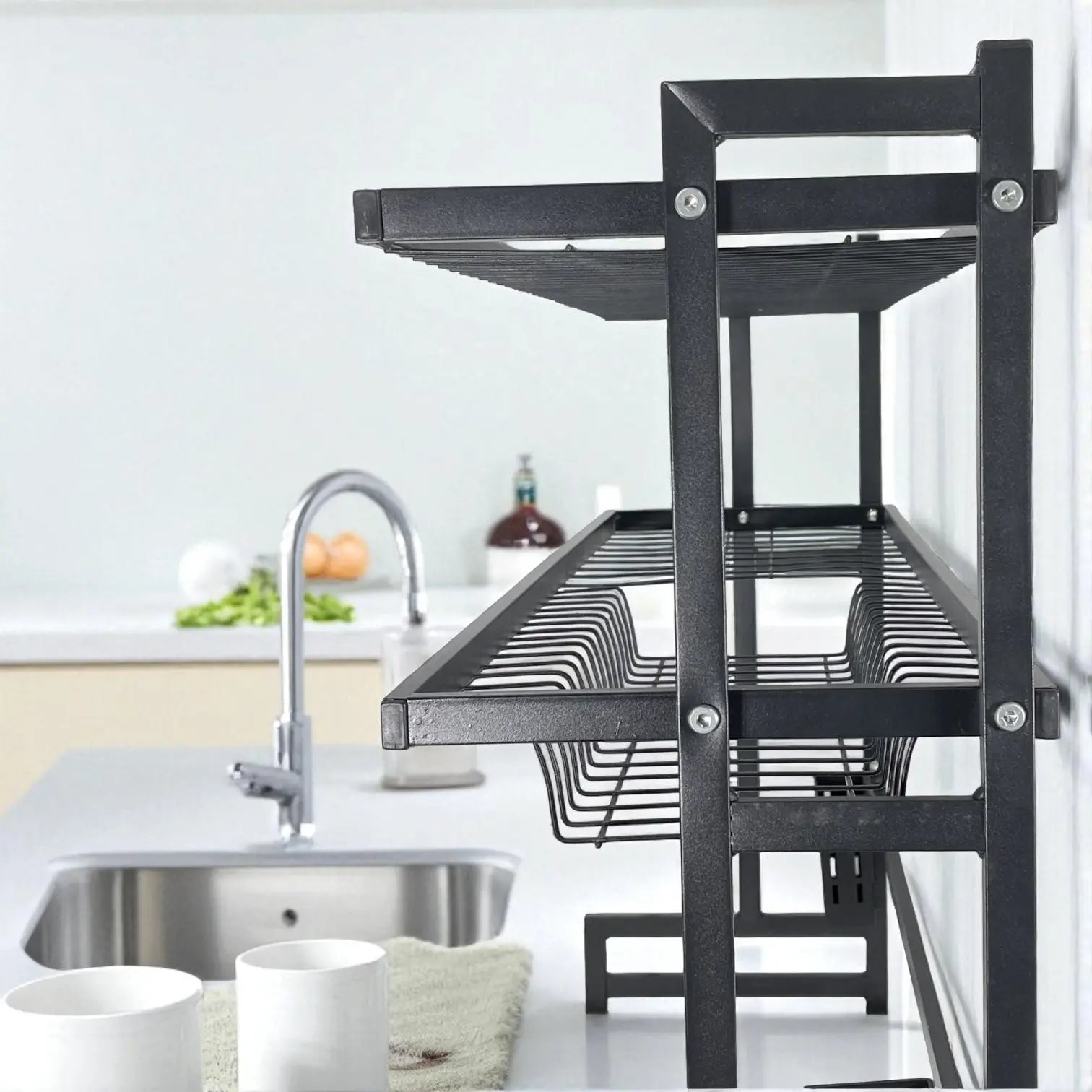 Primer plano lateral de la rejilla ondulada porta platos del escurridor MISOL negro; se aprecia la canastilla metálica inferior para cubiertos o utensilios.