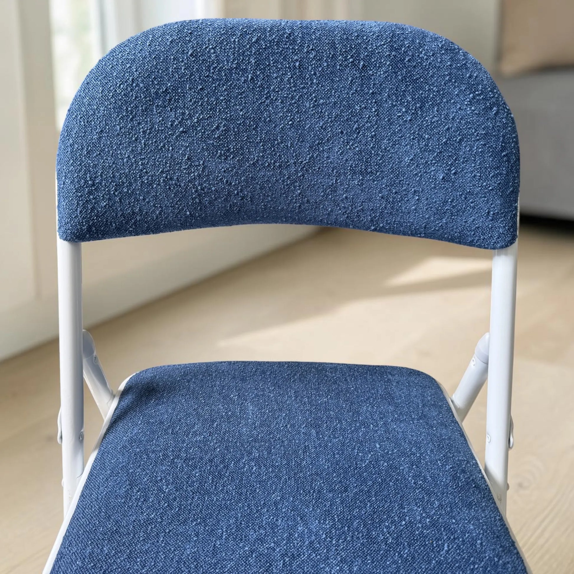 Detalle del tapizado azul en respaldo y asiento de silla plegable CH-3023-BLU con estructura blanca.