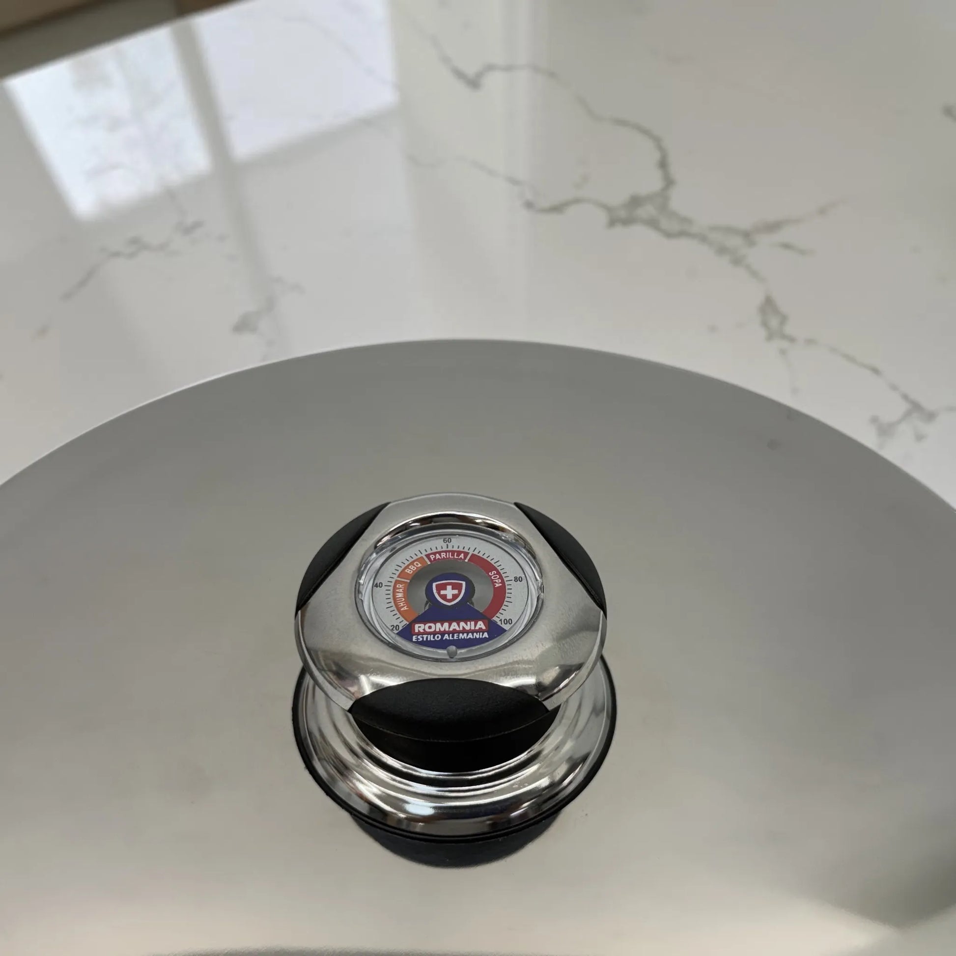 Primer plano del termómetro incorporado en la perilla de la tapadera del set de ollas Romania Estilo Alemania.