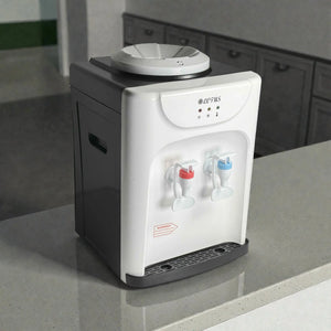Dispensador de agua Lotus LT-463 frío/caliente tipo sobremesa, frente blanco y laterales negros, vista lateral 3/4 con bandeja antigoteo y dos grifos; 36x27x24 cm