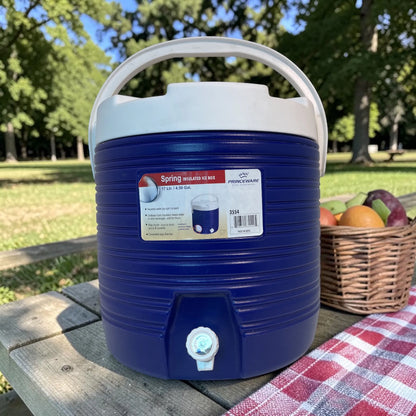 Dispensador térmico Princeware azul de 17 litros SKU 3554 con asa superior y grifo dispensador, colocado en mesa de picnic al aire libre.