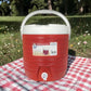 Vista frontal completa del dispensador térmico Princeware rojo de 17 litros SKU 3554 con asa blanca, tapa superior y grifo dispensador.