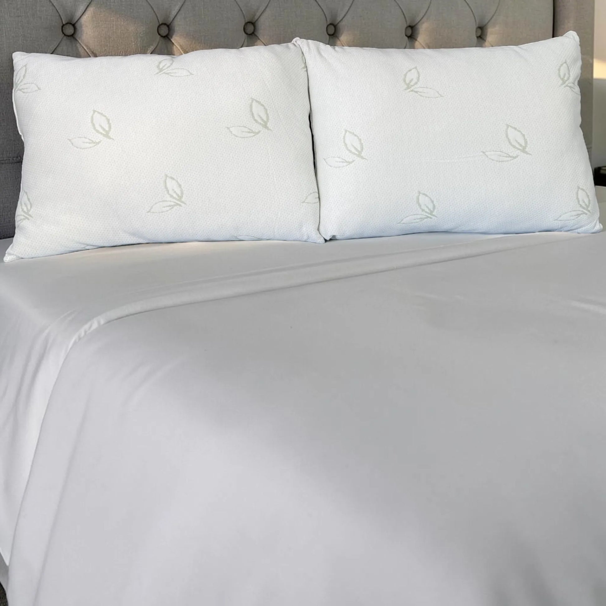 Dos almohadas de bambú Pacific Home blancas colocadas juntas en una cama, mostrando cómo se ven instaladas en un dormitorio.