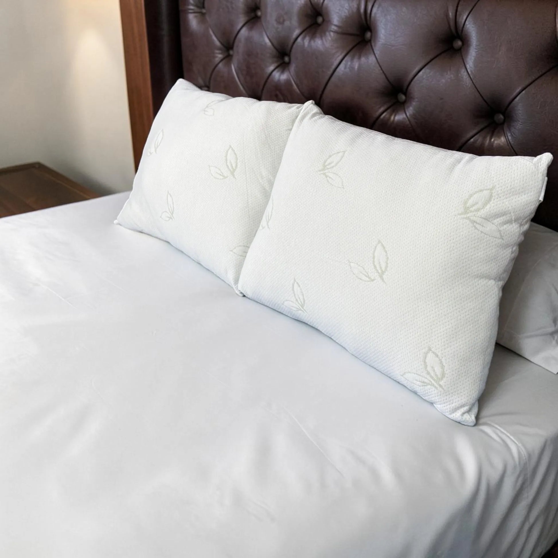 Dos almohadas de bambú Pacific Home blancas colocadas juntas sobre una cama, vistas en perspectiva diagonal para mostrar su volumen y apariencia instalada.
