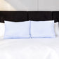 Dos almohadas refrescantes Pacific Home blancas con patrón celeste colocadas juntas sobre una cama con ropa blanca.