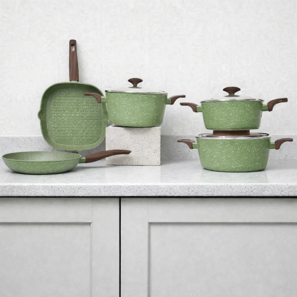 Set de cocina Epicure by Joseph Marcus Olive Collection verde oliva: sartén parrilla cuadrado, sartén redondo y ollas con tapa de vidrio templado, composición sobre encimera con fondo claro.
