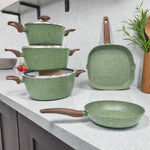 Set de ollas Epicure by Joseph Marcus Olive Collection color verde oliva con recubrimiento antiadherente, tres ollas con tapa de vidrio, sartén redondo y sartén parrilla cuadrado, foto lifestyle sobre encimera de cocina.