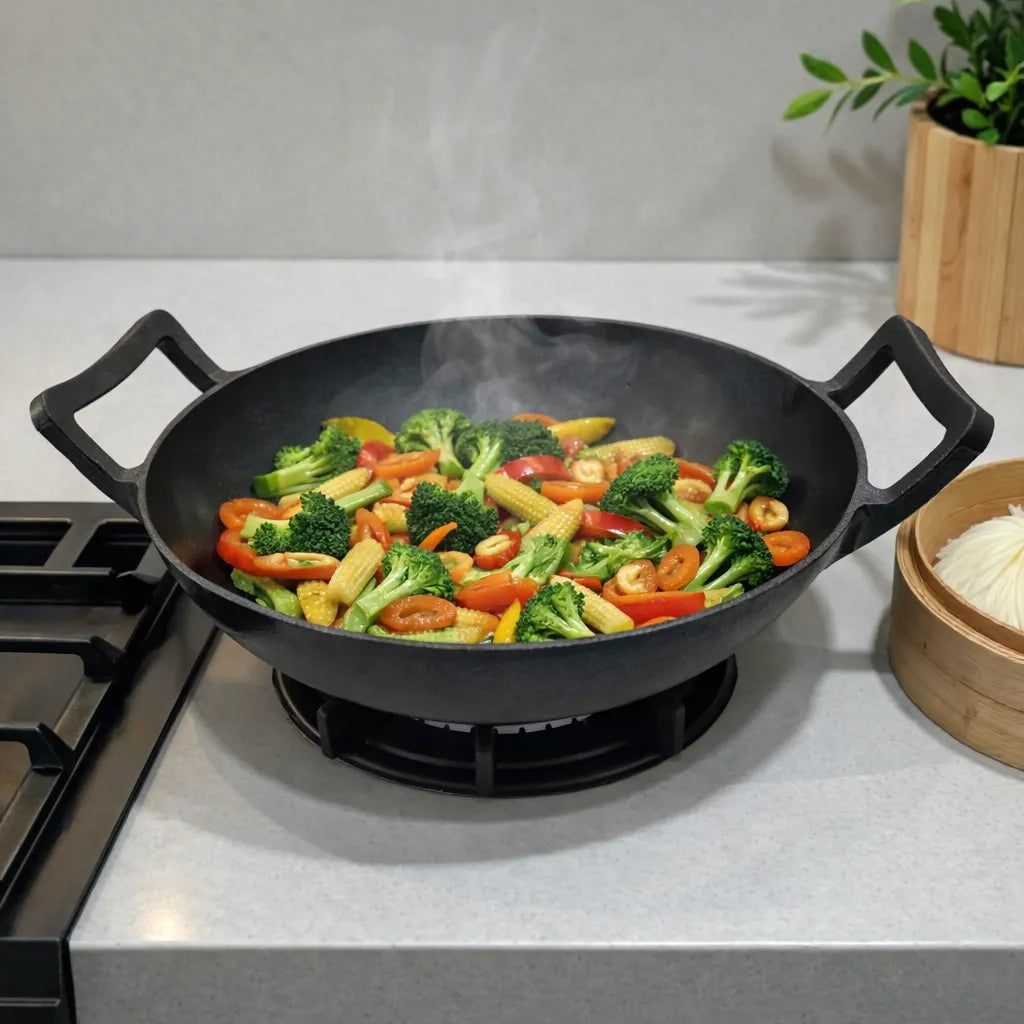 Wok de hierro fundido epicure by Joseph Marcus negro 31 cm sobre estufa, cocinando vegetales salteados con vapor visible, con dos asas laterales.