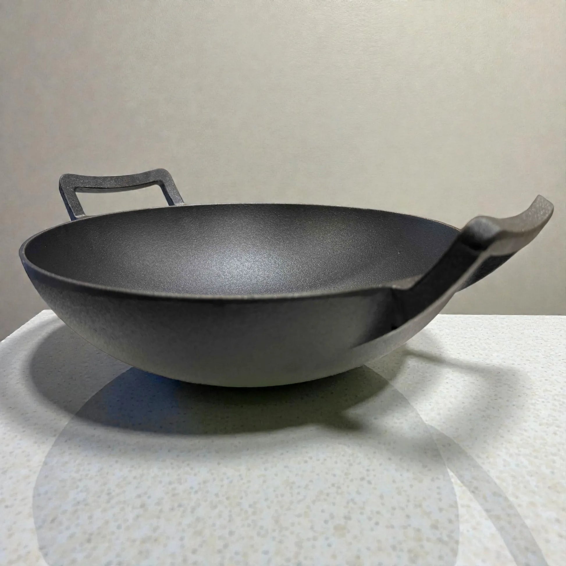 Wok de hierro fundido Epicure by Joseph Marcus color negro de 31 cm, vista en angulo bajo 3/4 resaltando el interior y las dos asas.