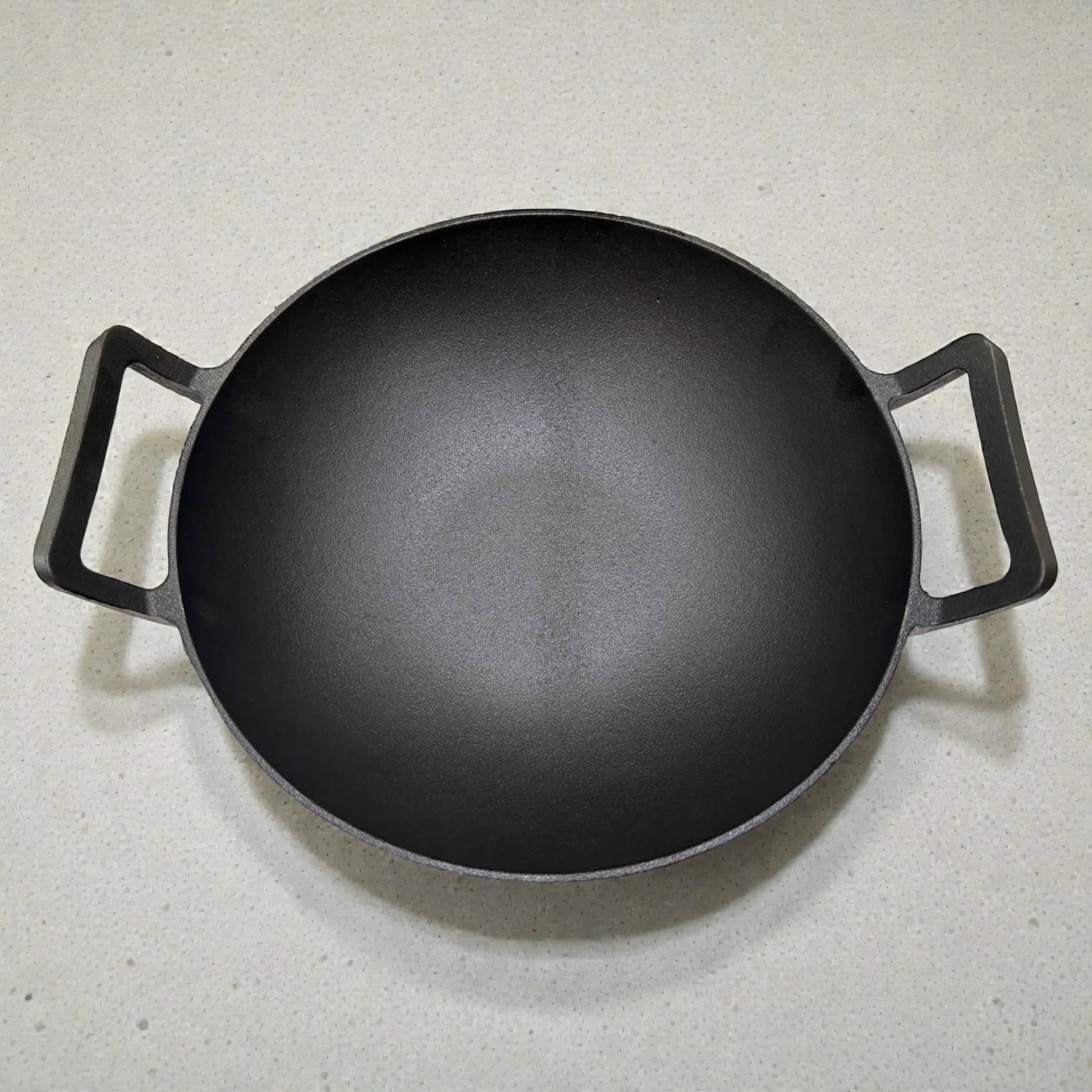 Vista superior del interior del wok de hierro fundido Epicure by Joseph Marcus negro 31 cm, mostrando la forma profunda y las dos asas laterales.