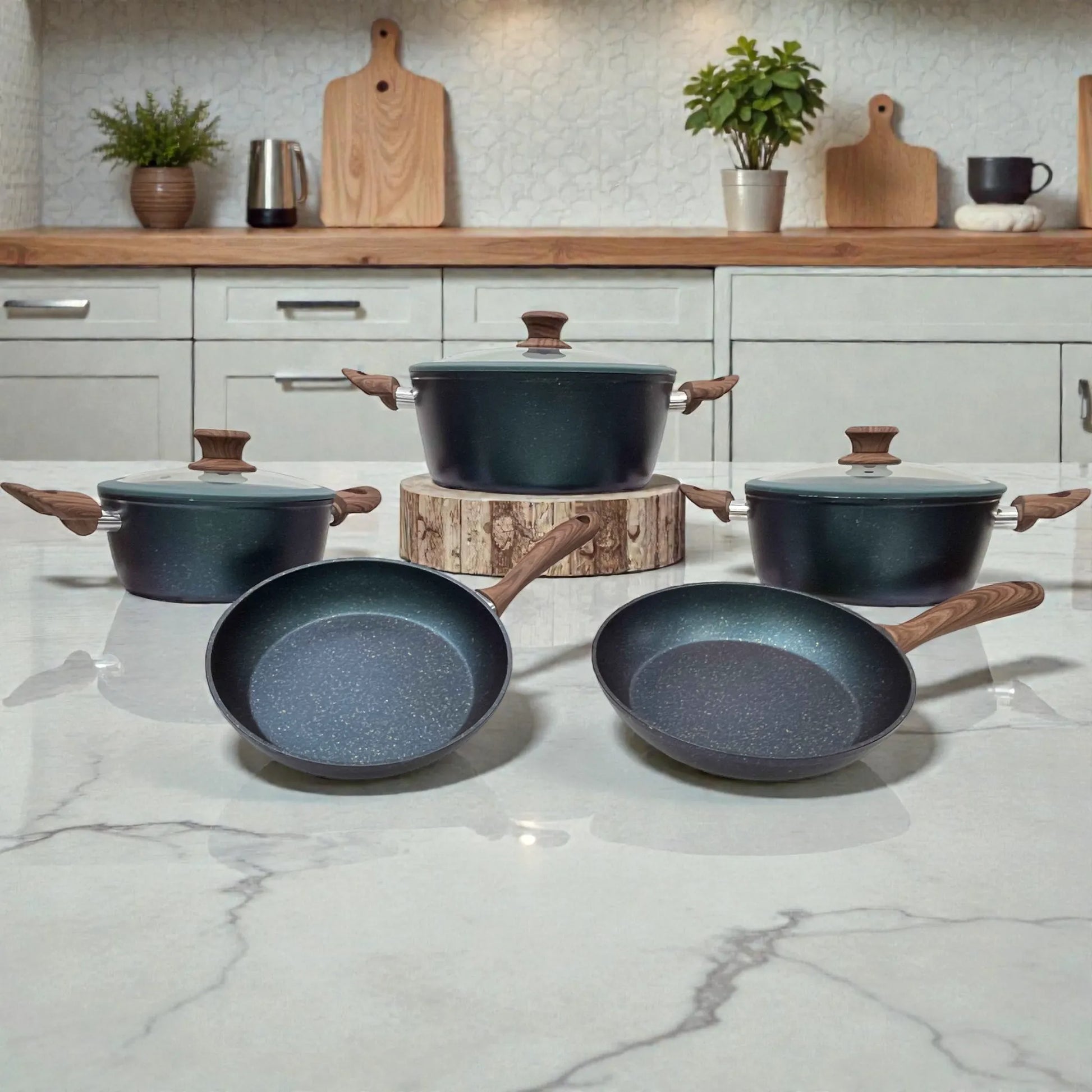 Set Epicure Zafiro 8 piezas en encimera: olla grande con tapa de vidrio al centro y dos ollas laterales con tapa, al frente dos sartenes antiadherentes, acabado azul oscuro moteado y mangos estilo madera.