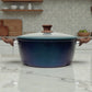 Olla Epicure Zafiro de 28 cm con tapa de vidrio y perilla efecto madera, cuerpo azul oscuro moteado y asas laterales tipo madera, ideal para cocinar y guisar.