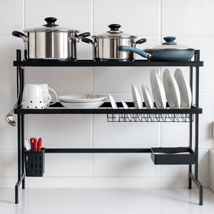 Vista frontal del escurridor de platos MISOL de dos niveles, acero color negro, tamaño 84×30×75 cm; nivel superior con ollas y sartén, nivel inferior con porta platos ondulado, canastilla metálica, porta cubiertos y bandeja lateral, instalado sobre el fregadero en cocina moderna.