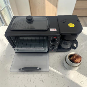 Vista superior de estación de desayuno LOTUS LT-2317 negra con horno abierto, cafetera integrada y accesorios sobre encimera clara.