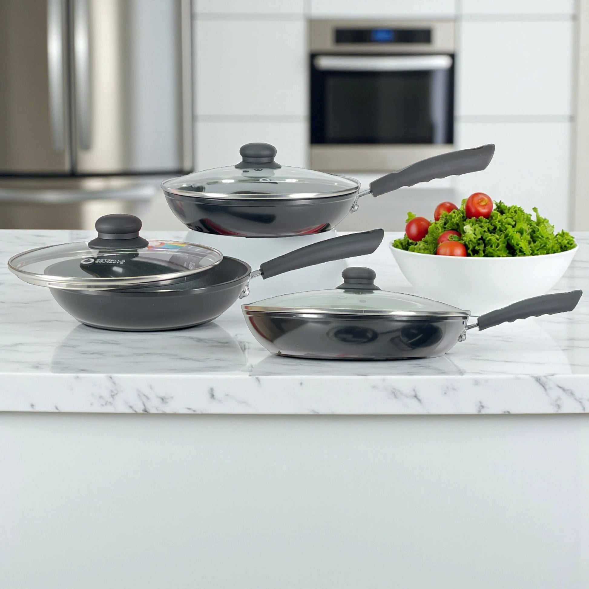 Juego de sartenes Estrella Gourmet con tapas de vidrio en encimera; tamaños 20, 24 y 30 cm, recubrimiento antiadherente de teflón, color negro, mangos ergonómicos.