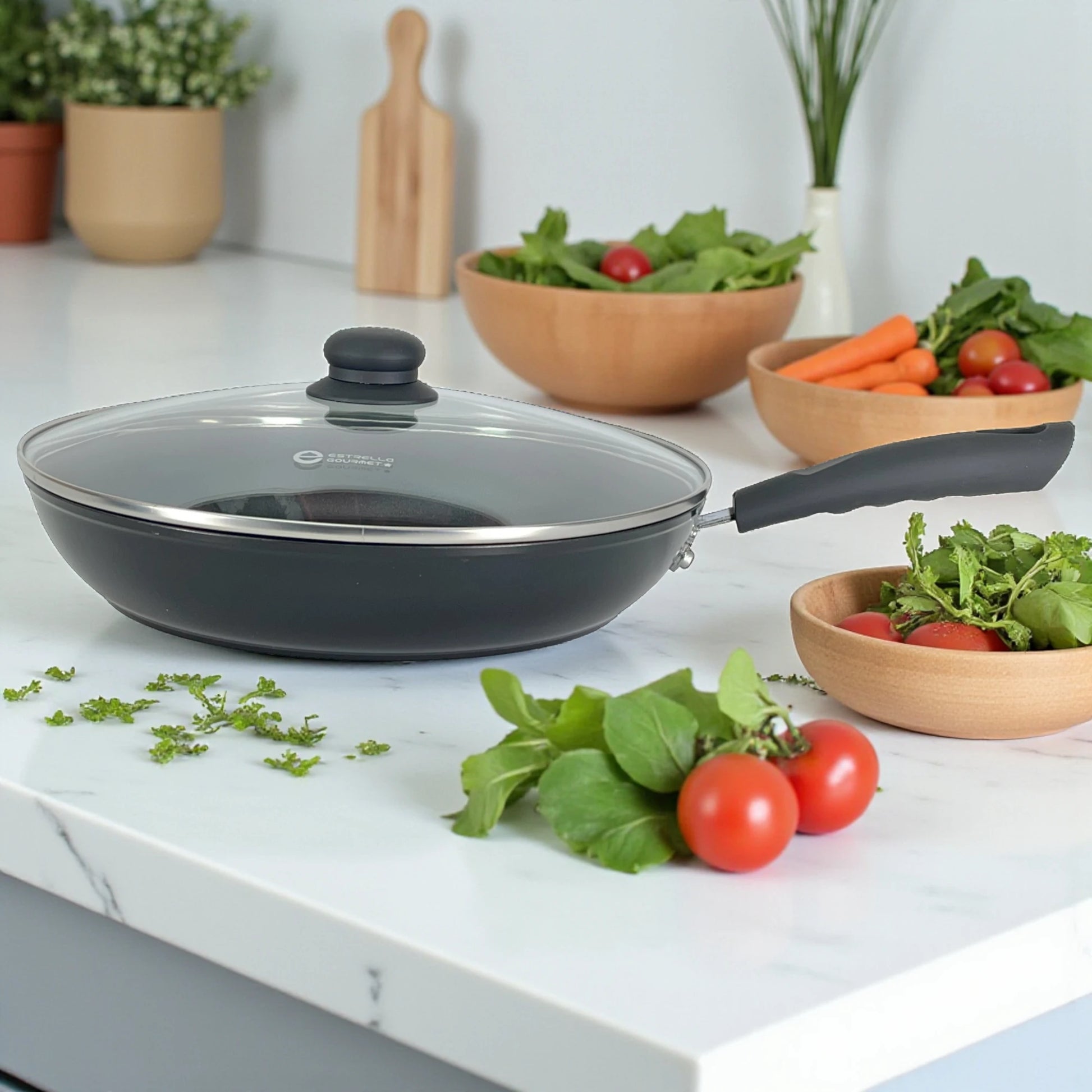 Sartén Estrella Gourmet de 30 cm con tapa de vidrio, aluminio forjado negro y mango ergonómico; vista lateral sobre encimera.