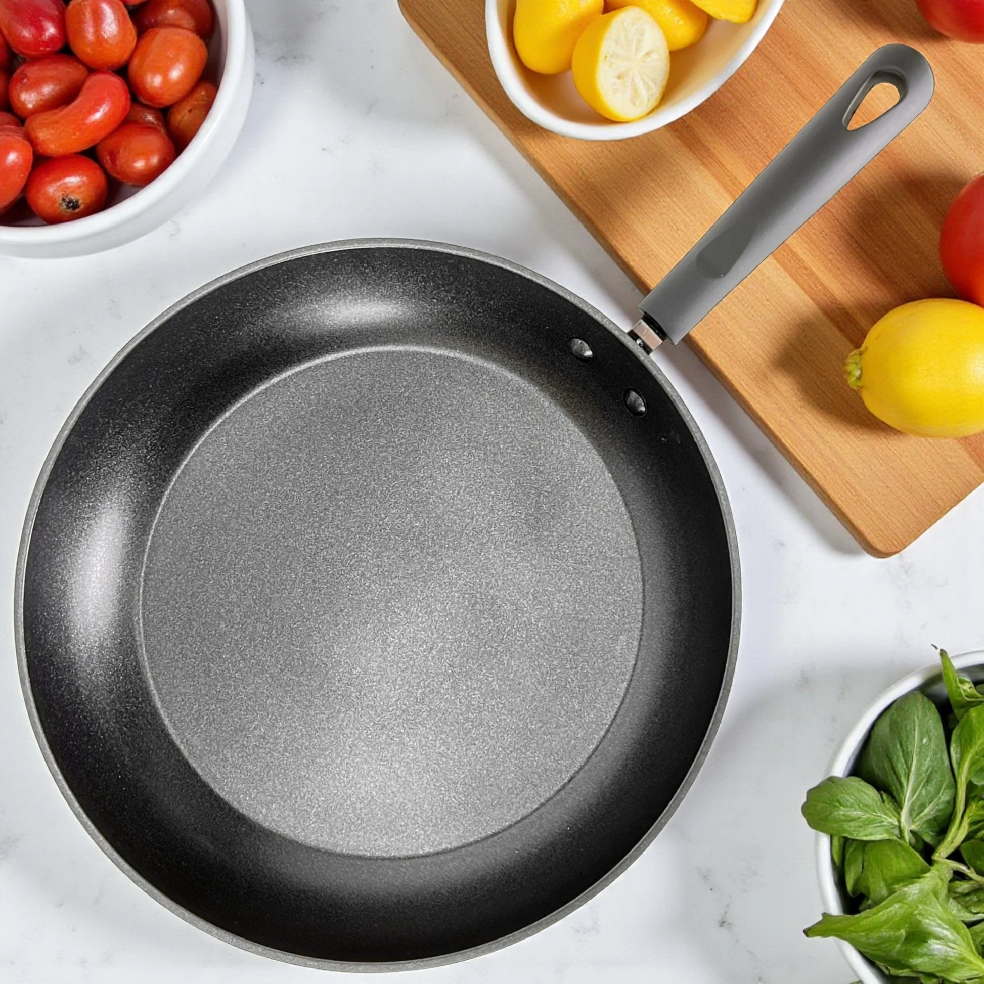 Detalle superior del interior antiadherente de teflón de un sartén Estrella Gourmet de 30 cm con mango de baquelita; textura gris moteada.