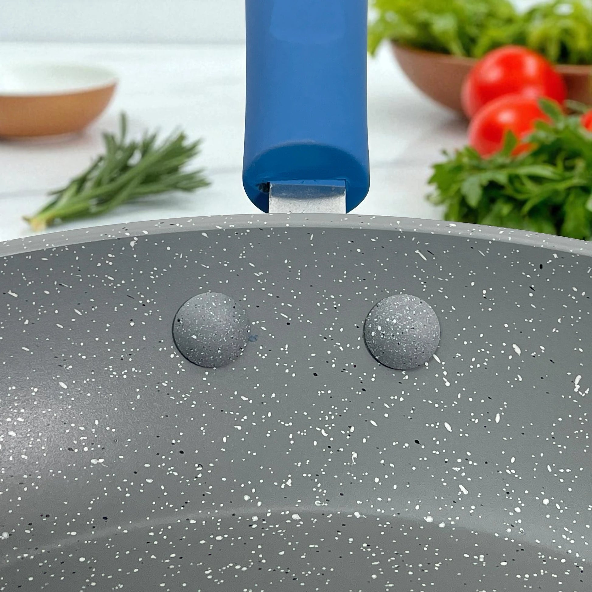 Vista interior del sartén Estrella Gourmet con recubrimiento antiadherente marmolizado gris y remaches internos que sujetan el mango azul; compatible con las medidas 20, 24 y 30 cm.