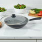 Sartén Estrella Gourmet con recubrimiento marmolizado y tapa de vidrio semiabierta, interior gris y mango de baquelita; bowls de ensalada al fondo, tamaños 20, 24 y 30 cm.