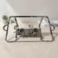 Estructura metálica de chafing dish en acero inoxidable con dos quemadores y asas laterales para catering.