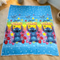 Frazada piel de borrego infantil Stitch “Aloha” en tonos azul con arcoíris y flores tropicales, 230x190 cm y 1500 g, fotografiada extendida en el piso; diseño repetido de Stitch al centro.