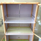 Detalle de la vitrina superior del gabinete de cocina LHC-RAC12-2 con escurridor metálico de dos niveles, bandejas plásticas y puertas de vidrio decoradas con diseño floral.