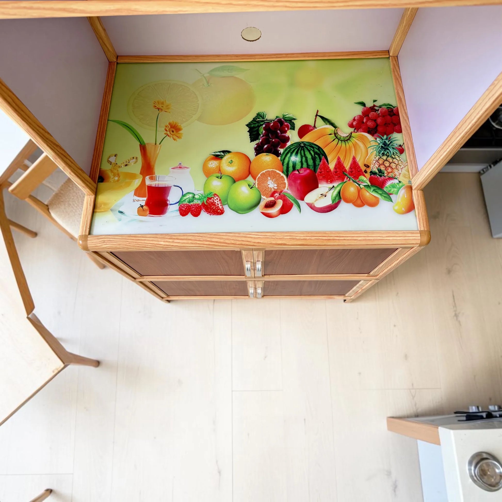 Vista superior de la repisa central del gabinete de cocina LHC-RAC12-2 con superficie decorada de frutas, espacio funcional para electrodomésticos y estructura vertical de cocina.
