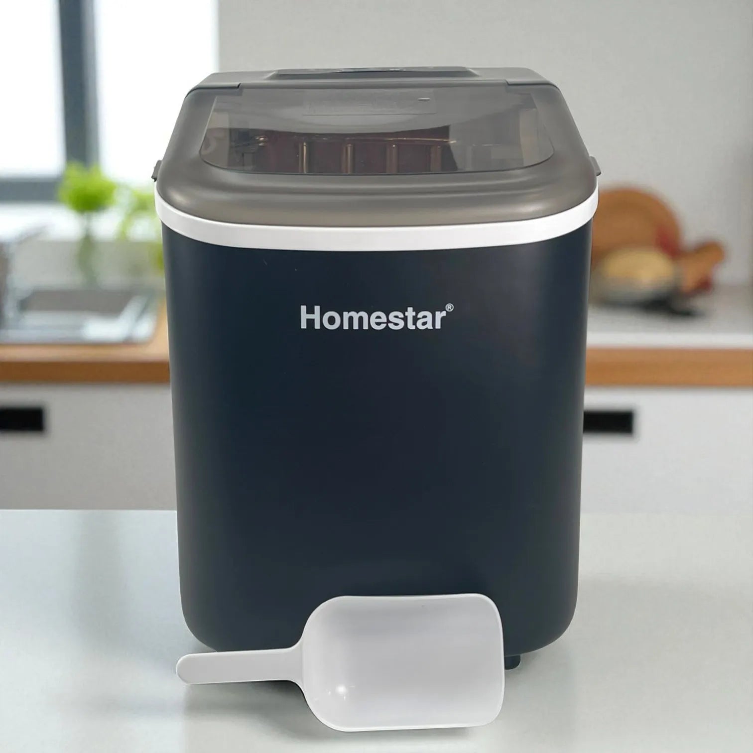 Máquina de hielo Homestar HS-Z6Y1B color negro, vista frontal con tapa cerrada y pala blanca frente al equipo en una encimera de cocina.