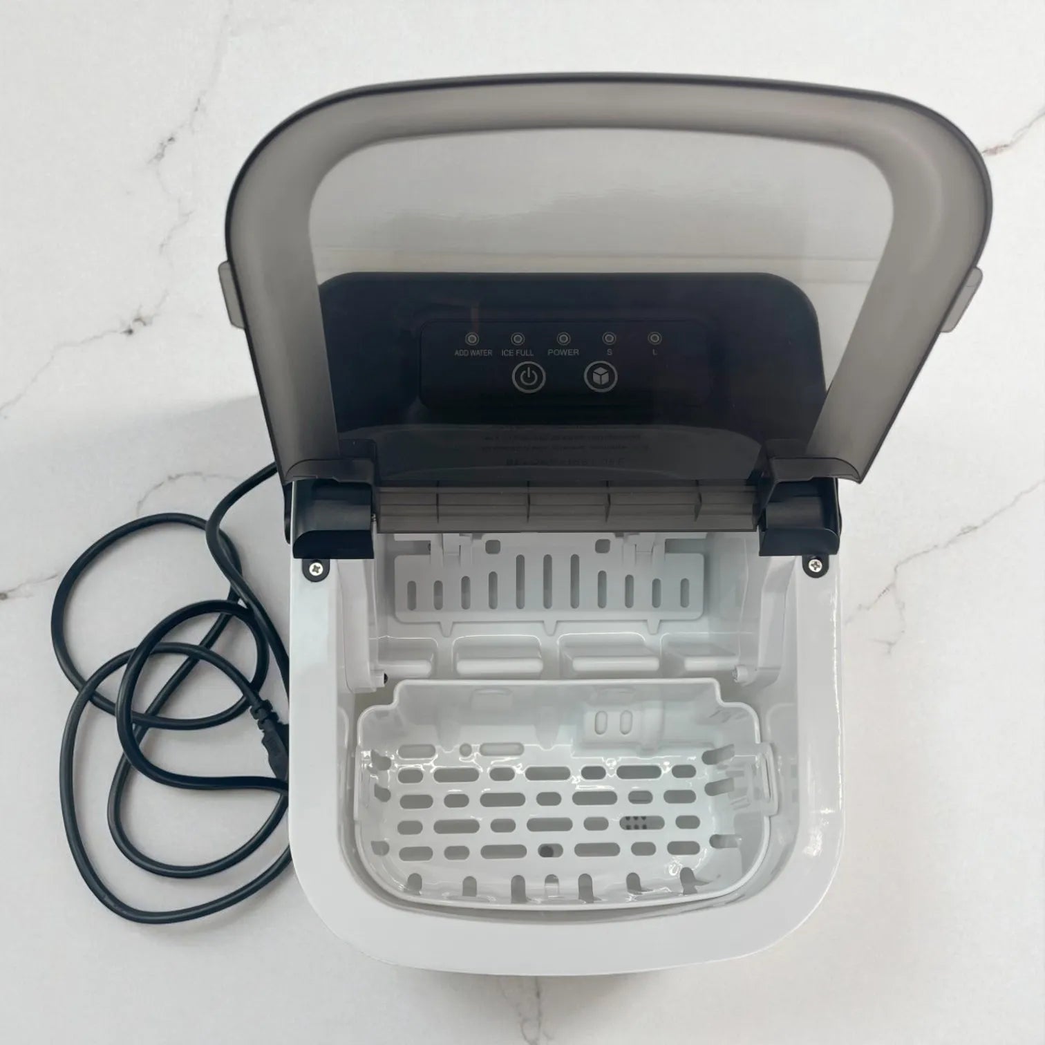 Toma cenital de la Homestar HS-Z6Y1B con la tapa abierta; se ve el interior con la bandeja perforada y el cable de alimentación a la izquierda.