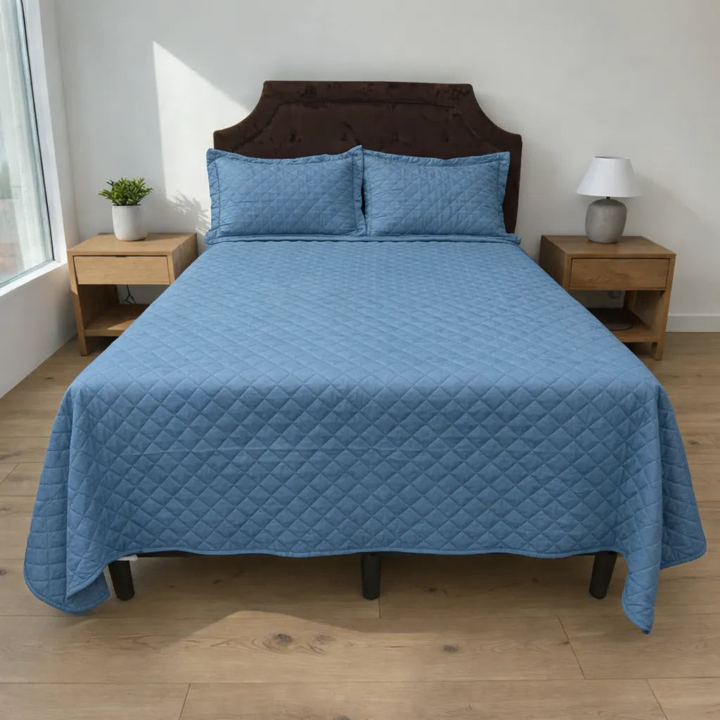 Cubrecama HPC Polo color azul acero de microfibra acolchada sobre cama, vista frontal con dos fundas de almohada a juego.