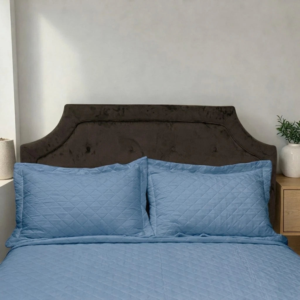 Acercamiento del cubrecama HPC Polo color azul acero con dos fundas de almohada acolchadas sobre cama.