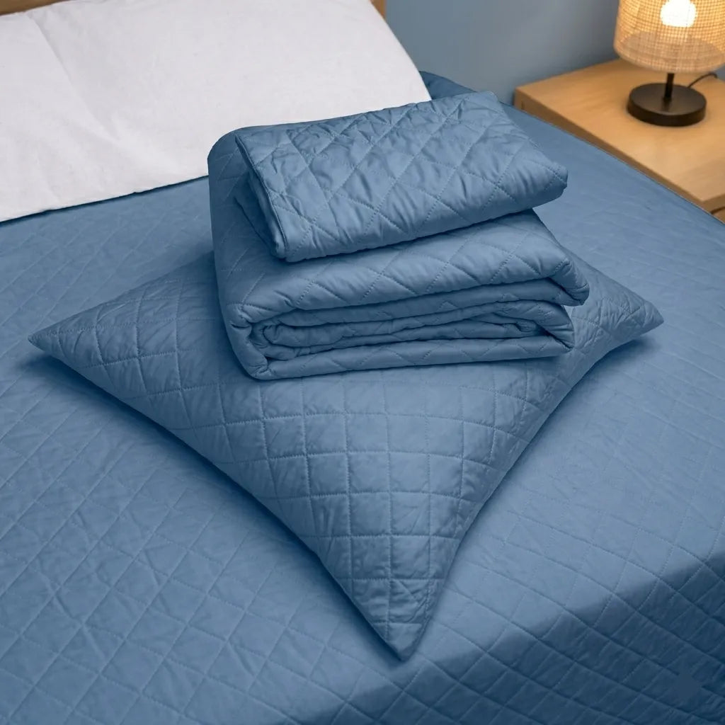 Detalle del cubrecama HPC Polo color azul acero doblado sobre almohada, con diseño acolchado y acabado de microfibra.