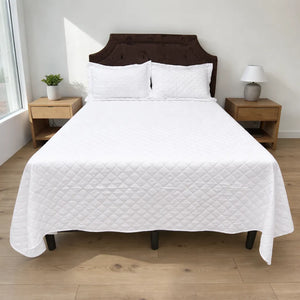 Cubrecama HPC Polo color blanco de microfibra acolchada sobre cama, vista frontal con dos fundas de almohada blancas.