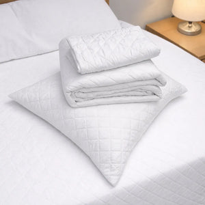 Detalle del cubrecama HPC Polo blanco doblado sobre almohada, con textura acolchada y acabado de microfibra.